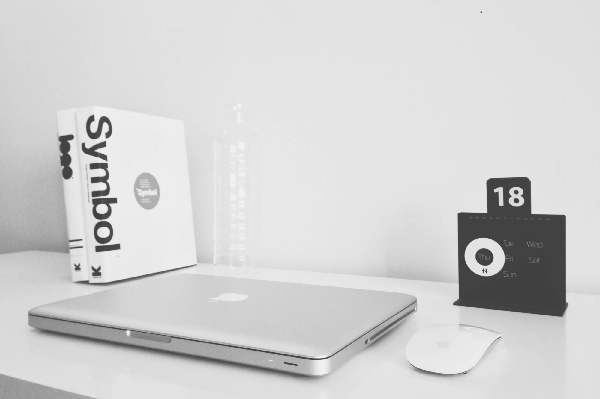 A laptop, mouse, and calendar on a desk.