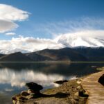 Wooden walkway leading to snow-capped mountains.