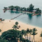Tropical beach with small island and bridge.