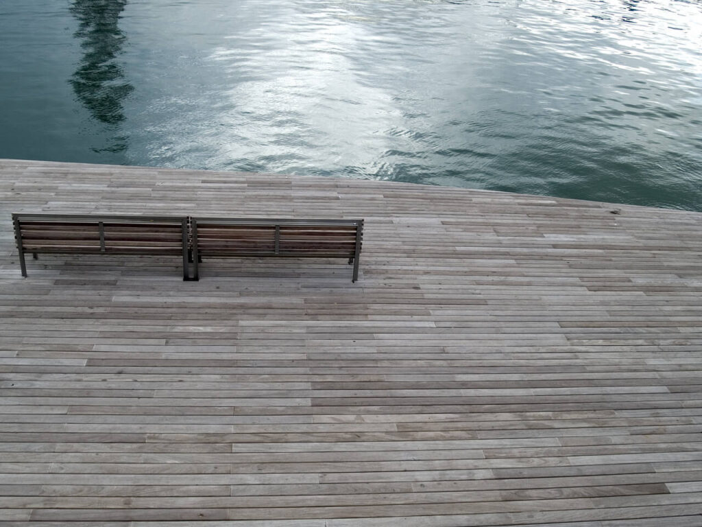 Two empty benches on a wooden dock.