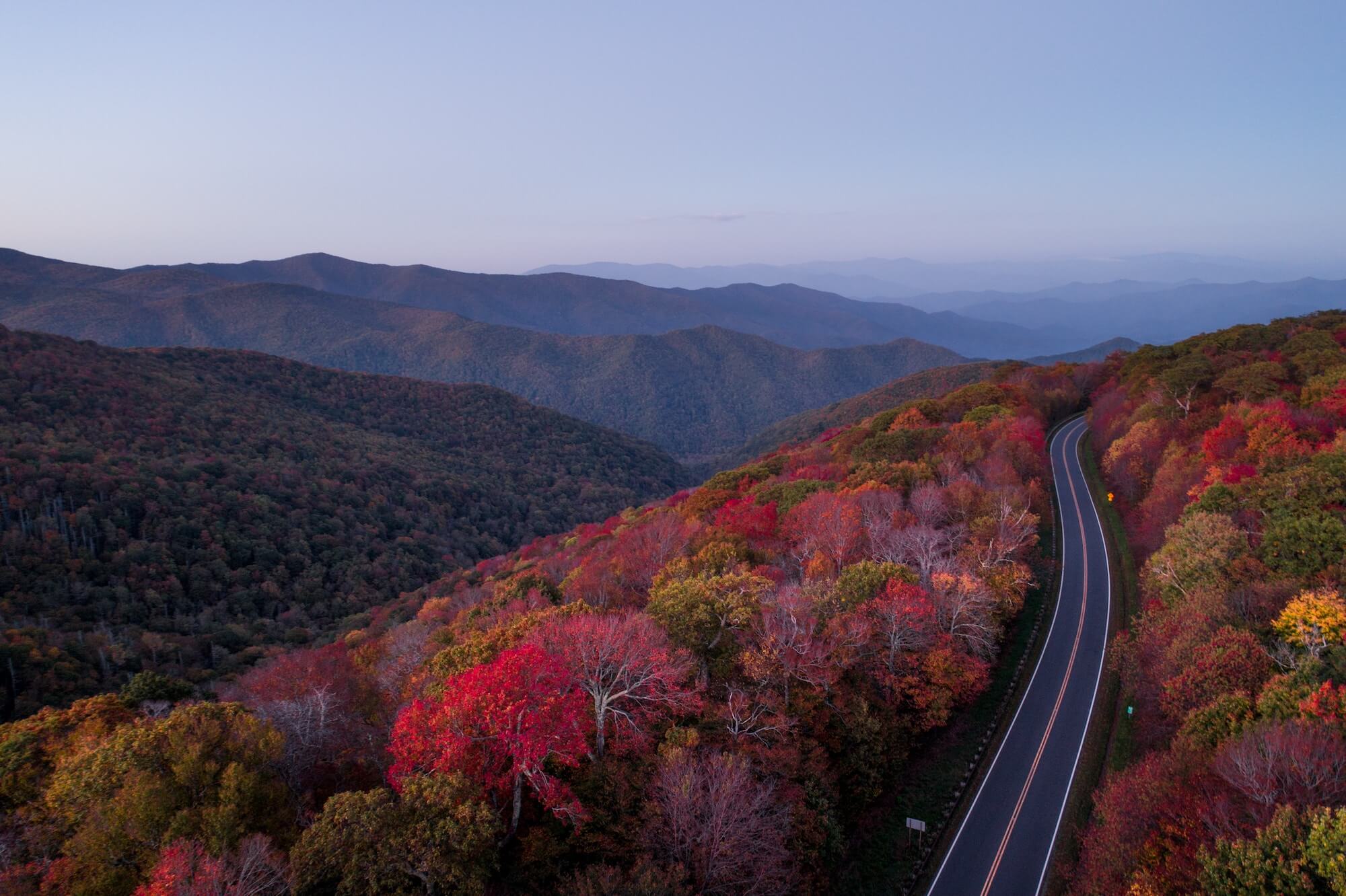 Winding road through fall foliage in mountains.
