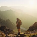 Hiker with backpack overlooking mountains.