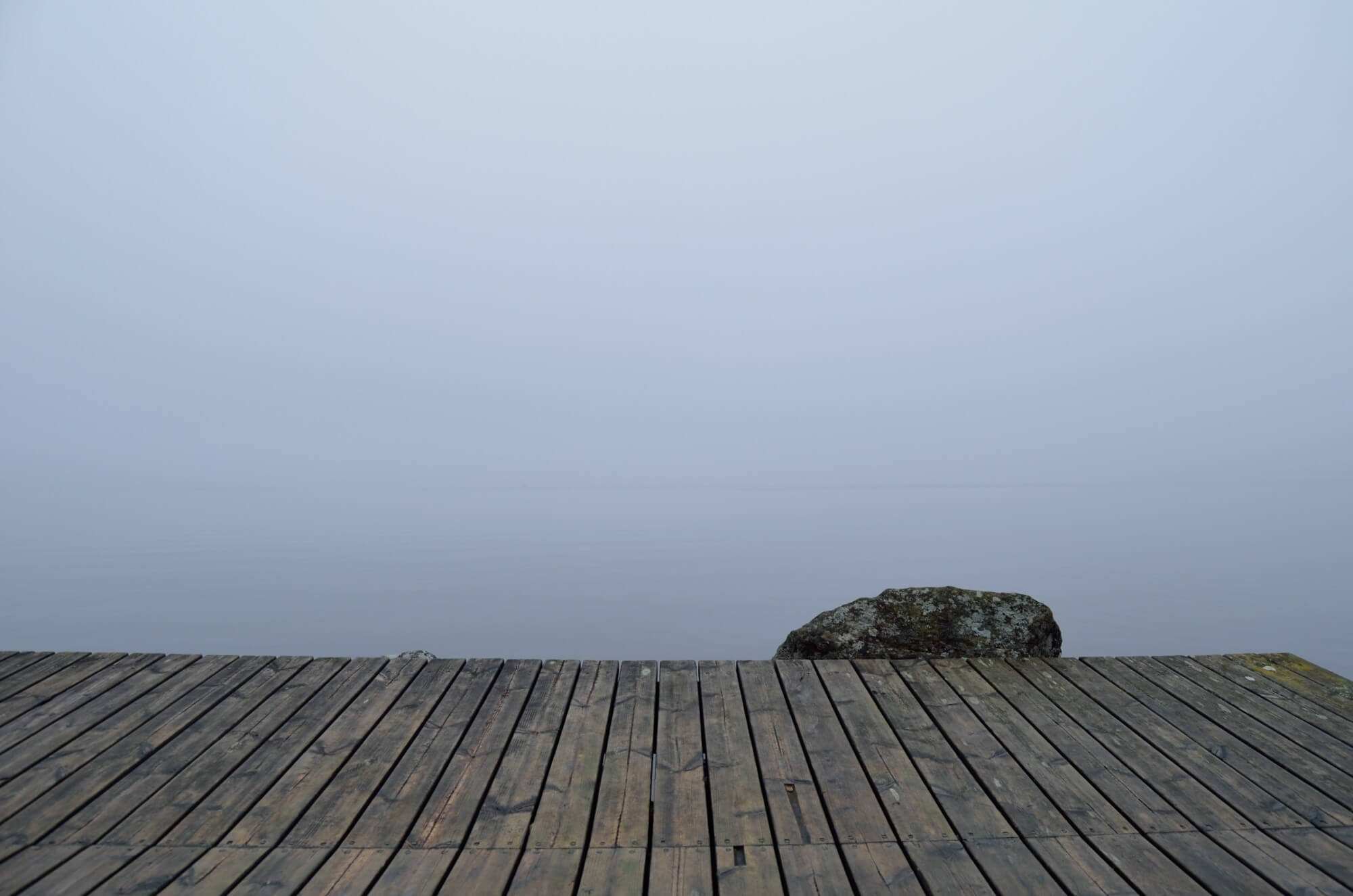 Wooden dock overlooking foggy lake.