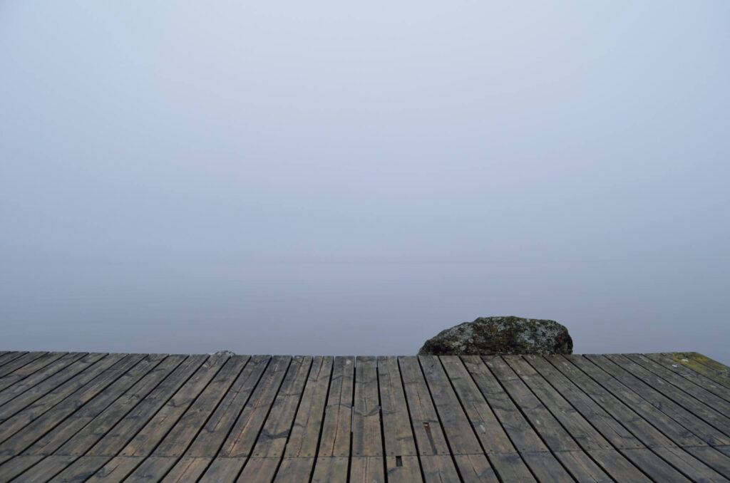 Wooden dock leading into foggy water.